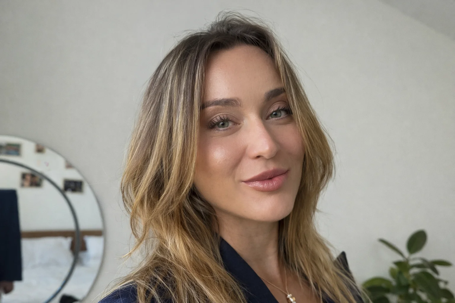 Paula Badosa smiling in a close-up portrait indoors, wearing a navy blazer and natural makeup.