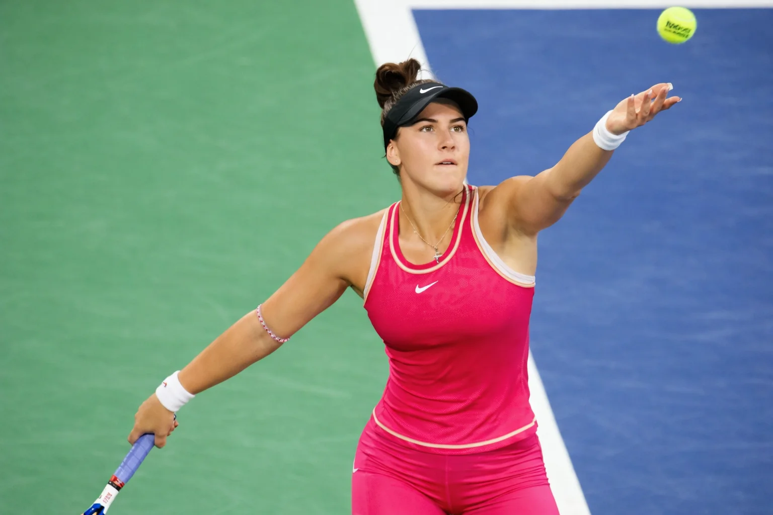 Bianca Andreescu serving in a bright pink outfit during a WTA tennis match on a hard court.