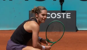 Caty McNally crouching on red clay court holding tennis racket during 2026 match