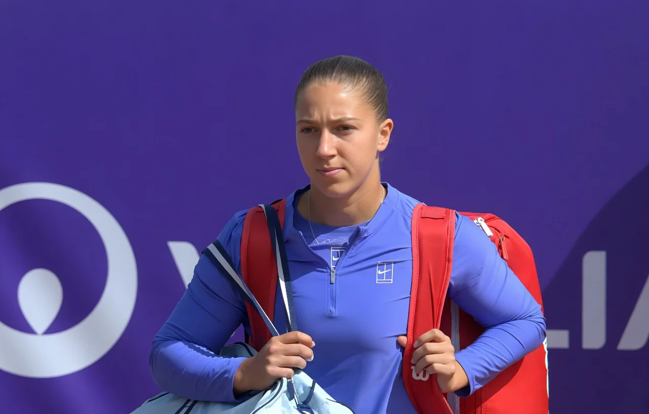 Diane Parry at the Strasbourg Open wearing a blue long-sleeve tennis top and carrying her gear, looking focused before a match