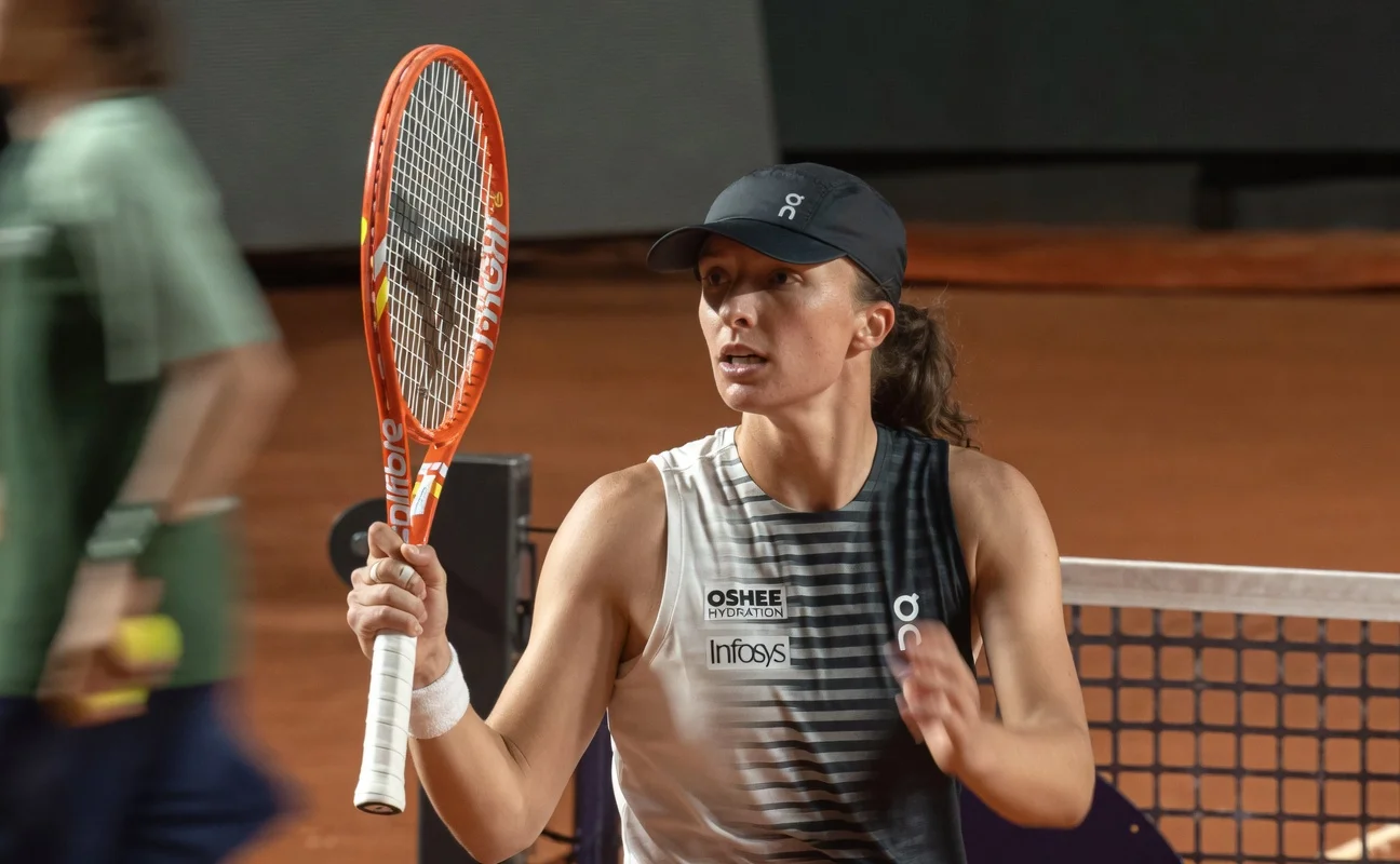 Iga Swiatek holding her racket in celebration after winning a match at the Italian Open on clay