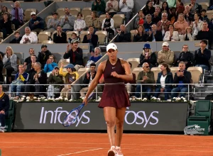 Madison Keys celebrates on a clay court at the French Open as the crowd applauds during a professional tennis match.