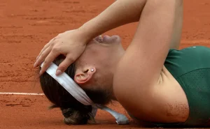 Marta Kostyuk lies on the red clay court in Madrid celebrating her first WTA 1000 title victory, hand on head in disbelief after winning the final