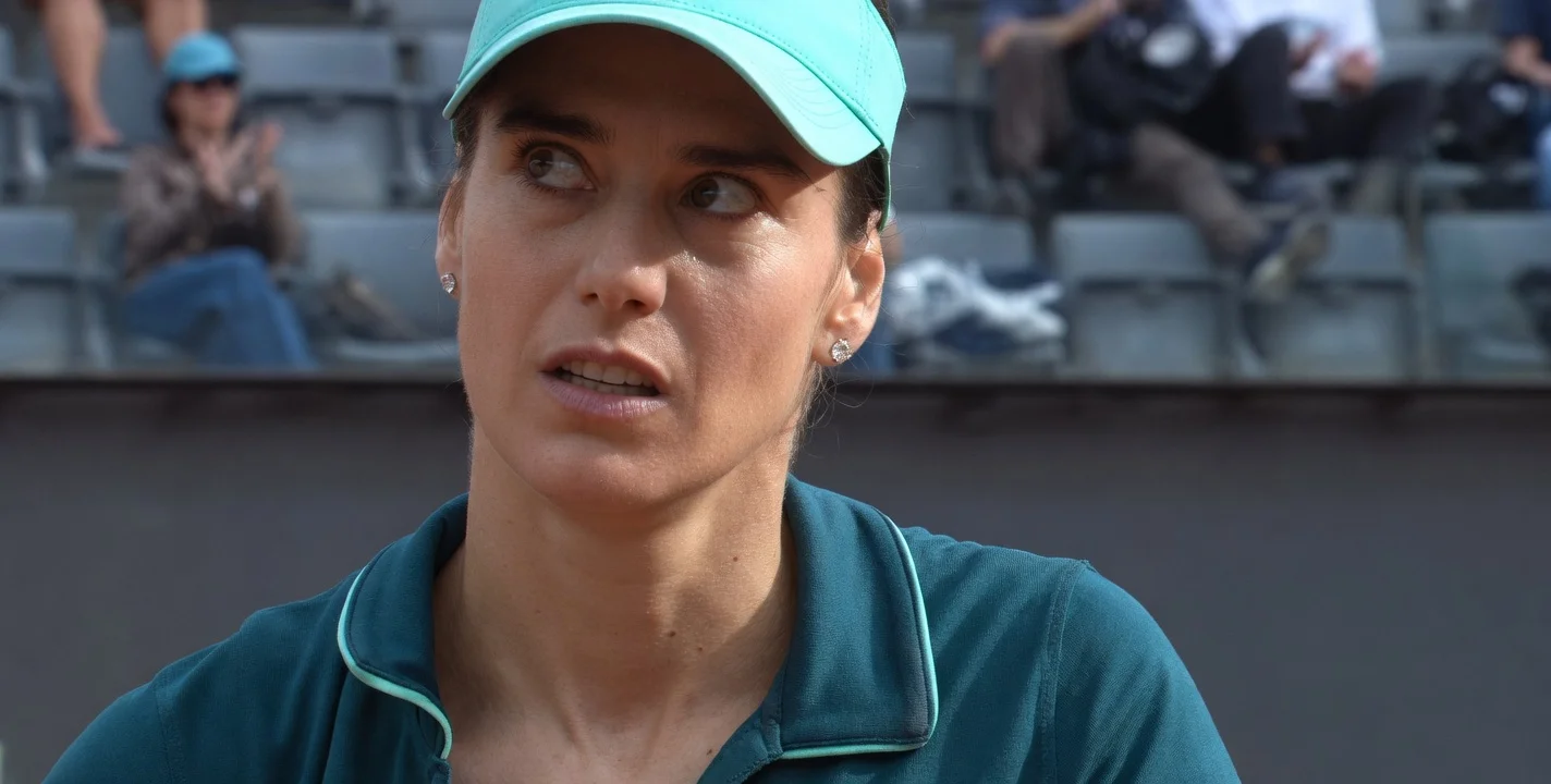 Sorana Cirstea at 36 years old during her match against Aryna Sabalenka in Rome 2026, wearing a turquoise visor and polo shirt, focused expression on court